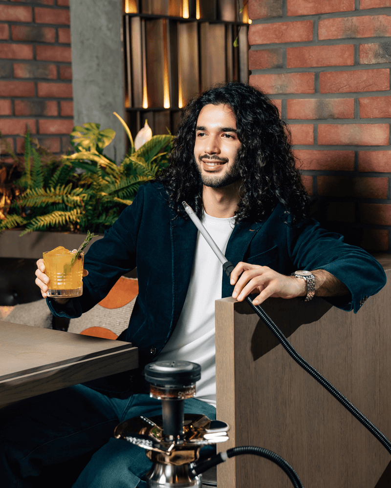 Man enjoying shisha with a drink in stylish Dubai