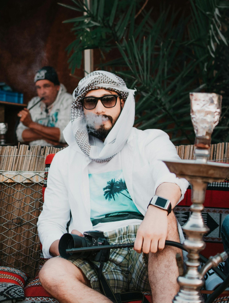 Man smoking shisha pipe indoors with visible smoke, highlighting nicotine in shisha and its health effects